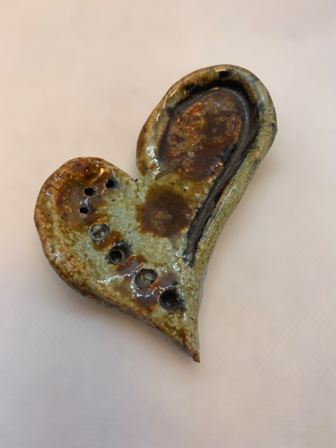 Corazón pequeño, celeste con manchas cafés, perforaciones. Reverso celeste mate