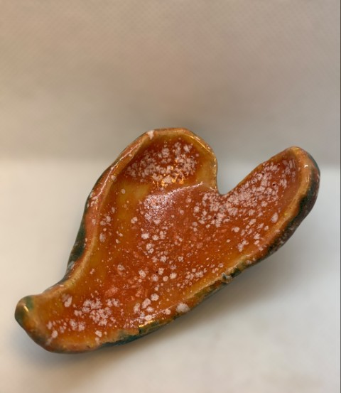 Corazón alargado. Interior naranja con puntos blancos. Reverso turquesa traslúcido