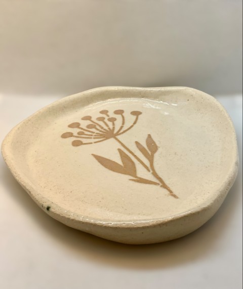 Plato plano con stencil de flor en tono anaranjado. Plato irregular, bordes curvos