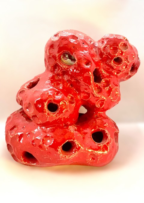 Escultura pequeña roja con perforaciones y bajorelieves circulares