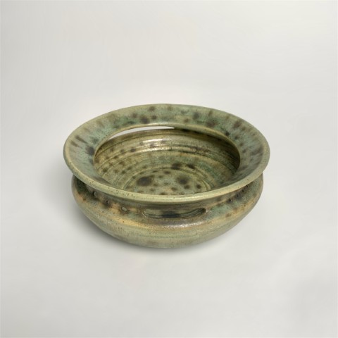 Plato verde con manchas cobre y perforaciones.